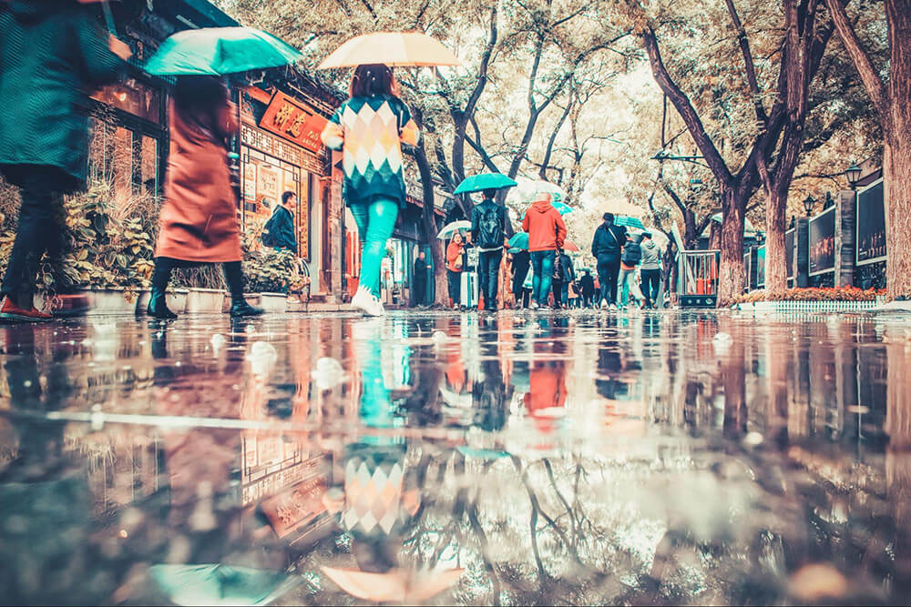 雨の中、傘をさして街中を歩く人々