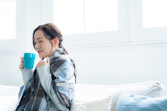 体を温めながらホットドリンクを飲む女性