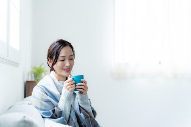 家の中で温かい飲み物を飲む女性